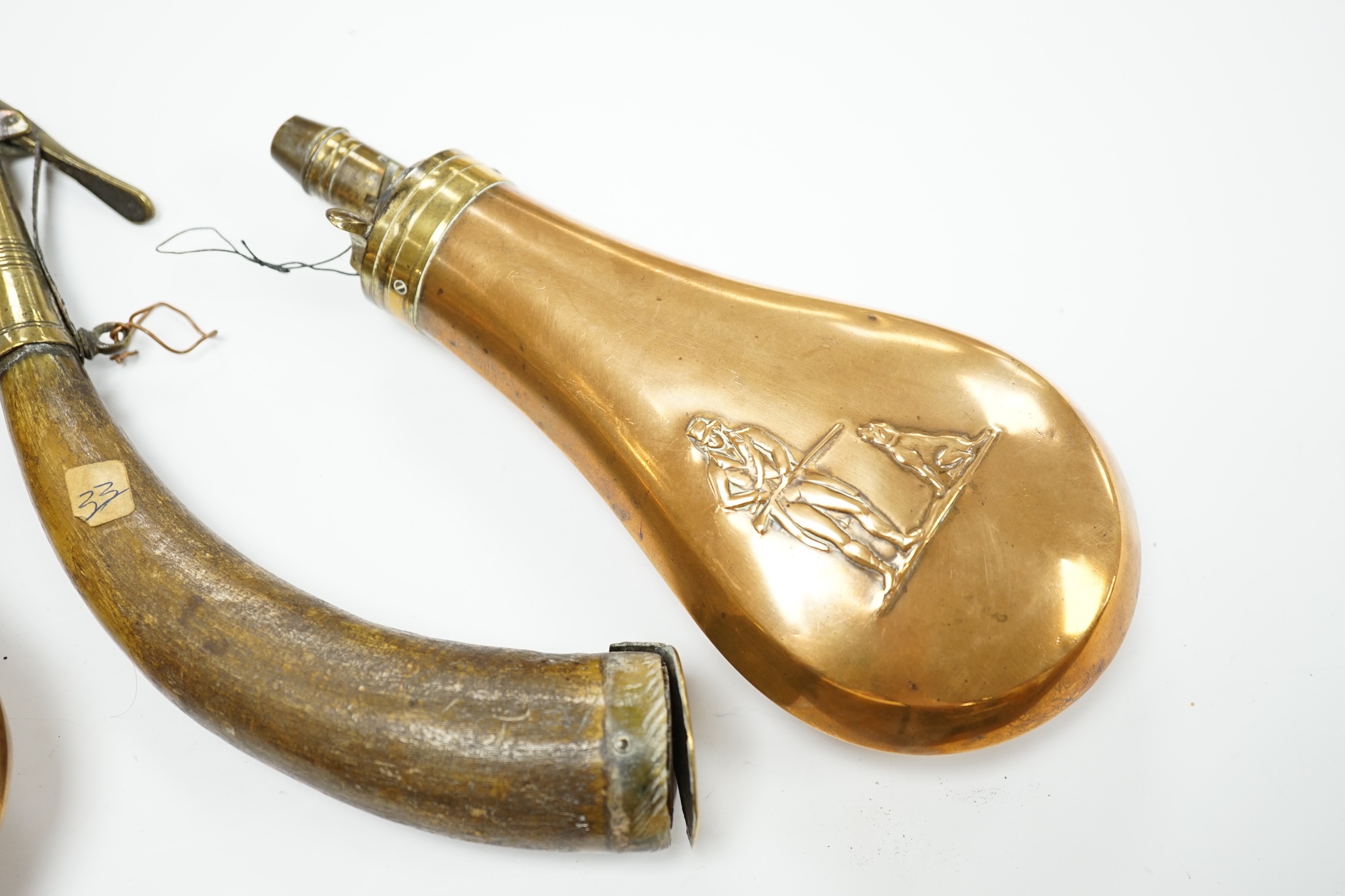 Five 19th century powder flasks; three copper and brass flasks, two with embossed decoration to the bodies, a leather covered flask and a horn Royal Artillery priming horn. Condition - poor to fair